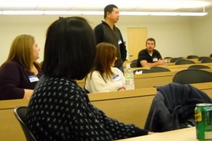 One of the attendees gives his 60-sec elevator speech; onlookers look on